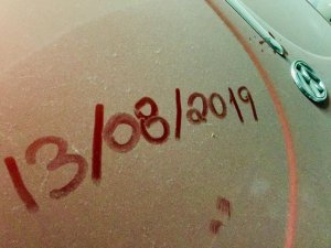 foto do parabrisa do carro empoeirado com a data escrita 13/08/2019