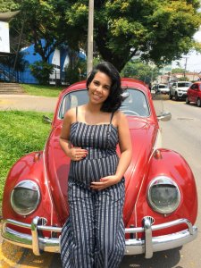 Foto da Patrícia grávida, segurando a barriga, em frente ao fusca.